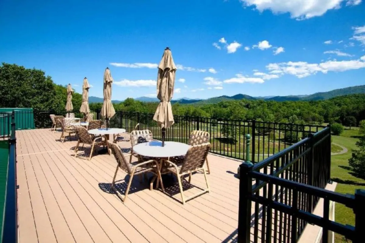 An inviting outdoor dining area with tables shaded by umbrellas set against a picturesque mountain backdrop. The scene offers tranquil vibes, with guests relaxing and enjoying the natural surroundings, perfect for summer gatherings or spring and fall meals outdoors.