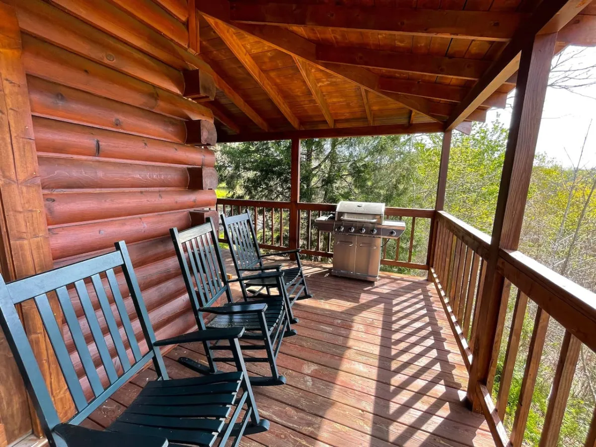 A welcoming exterior porch with classic wooden rocking chairs, a grill ready for barbecues, and a sturdy wooden railing. The setting encourages outdoor meals and leisurely moments, with the soft glow of sunset suggesting a day well spent.